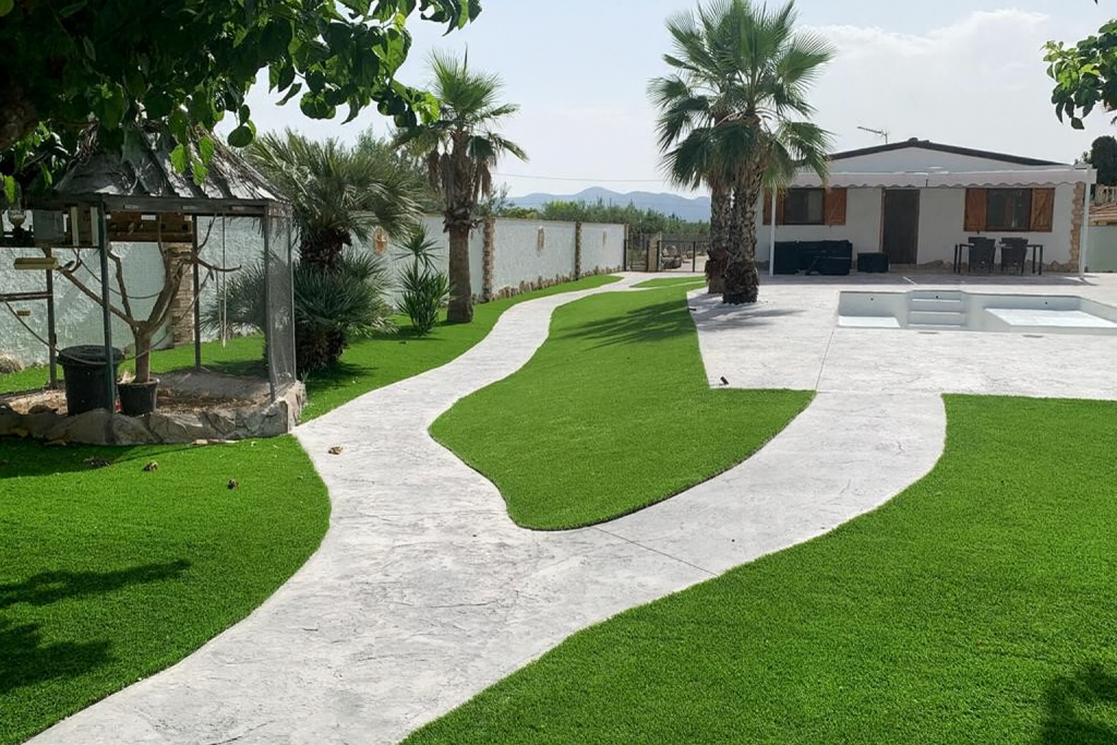 Jardín con camino de hormigón impreso junto a vivienda, instalación por Pavimentos Costa Blanca